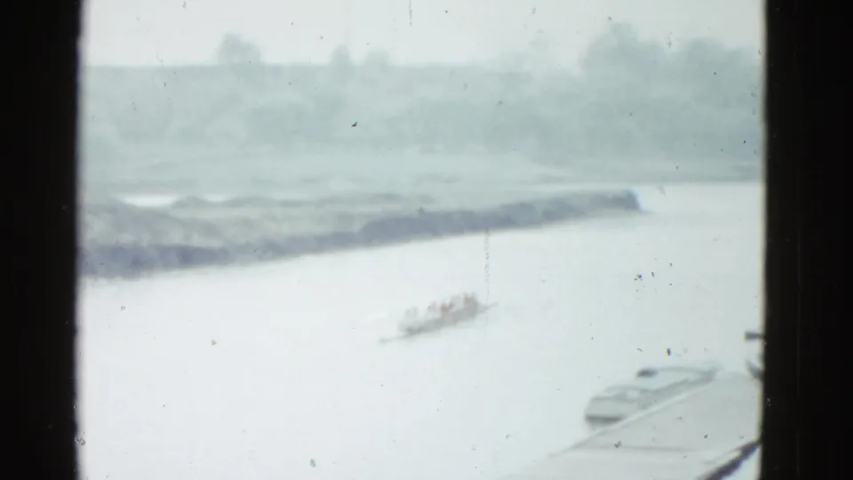 Final frame shows the rowing crew receding across the river in supported 1951 Boston footage, with boats and shoreline still faintly visible.