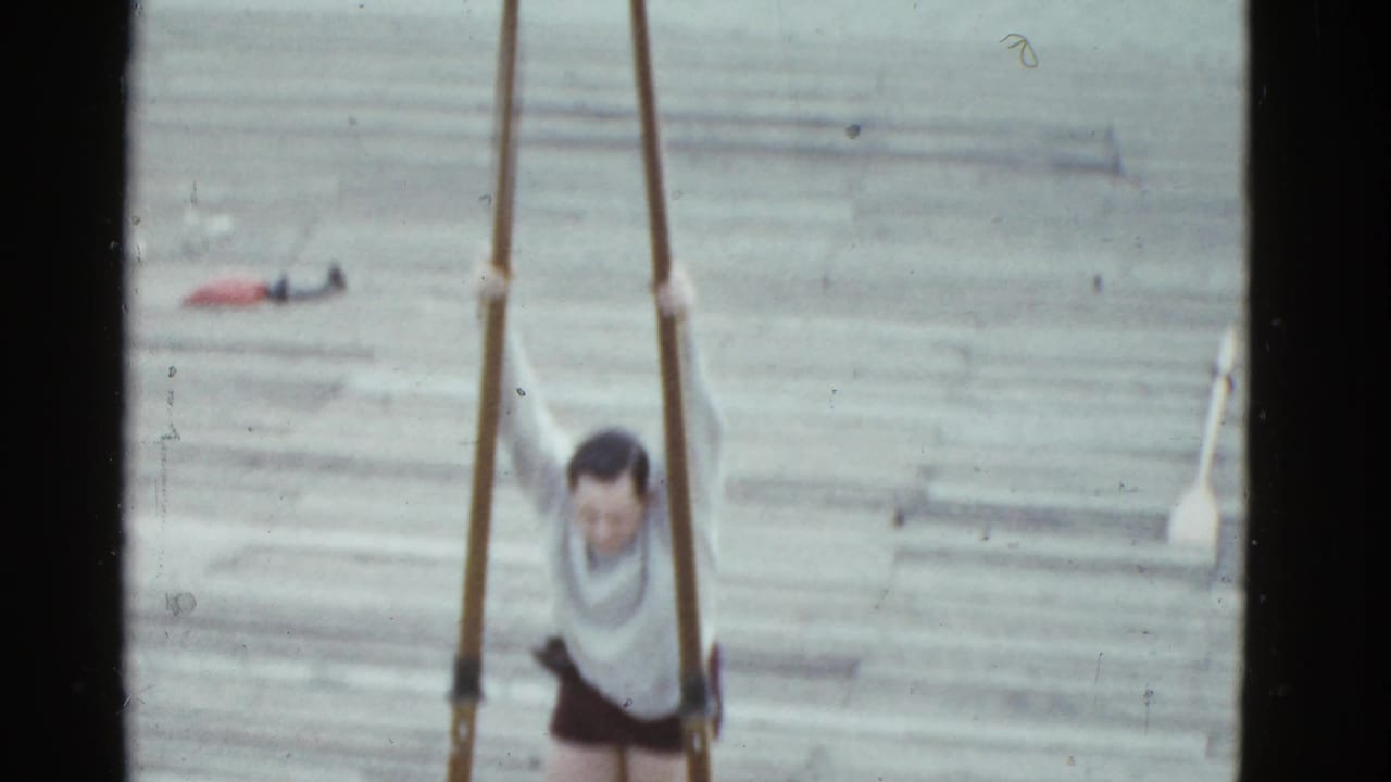 The man remains on the Boston dock, partly softened by the 8mm scan, with long oars framing him vertically.