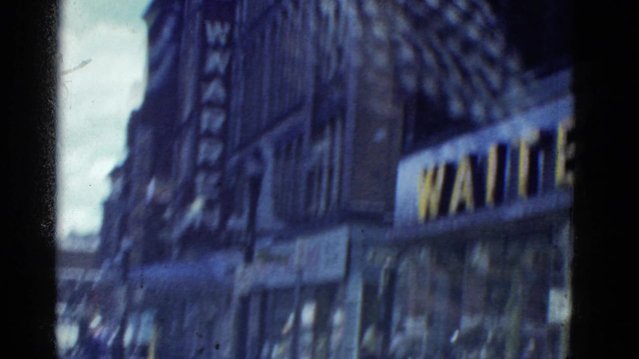 Blurred street view with tall buildings, storefront awnings, and a partial vertical sign.
