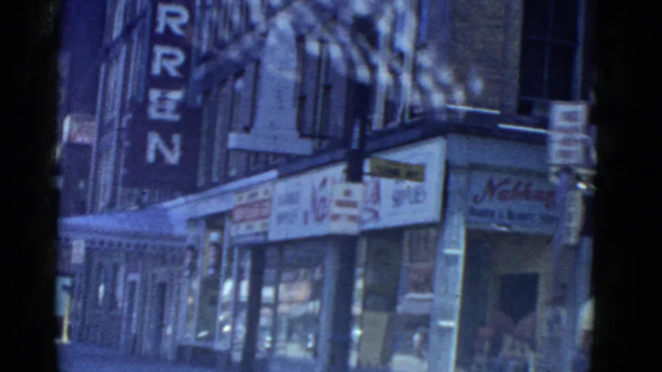 1951 Boston street corner showing the vertical Hotel Warren sign, Nathan's storefront signage, a barber supplies sign, building facades, and pedestrians near the sidewalk.