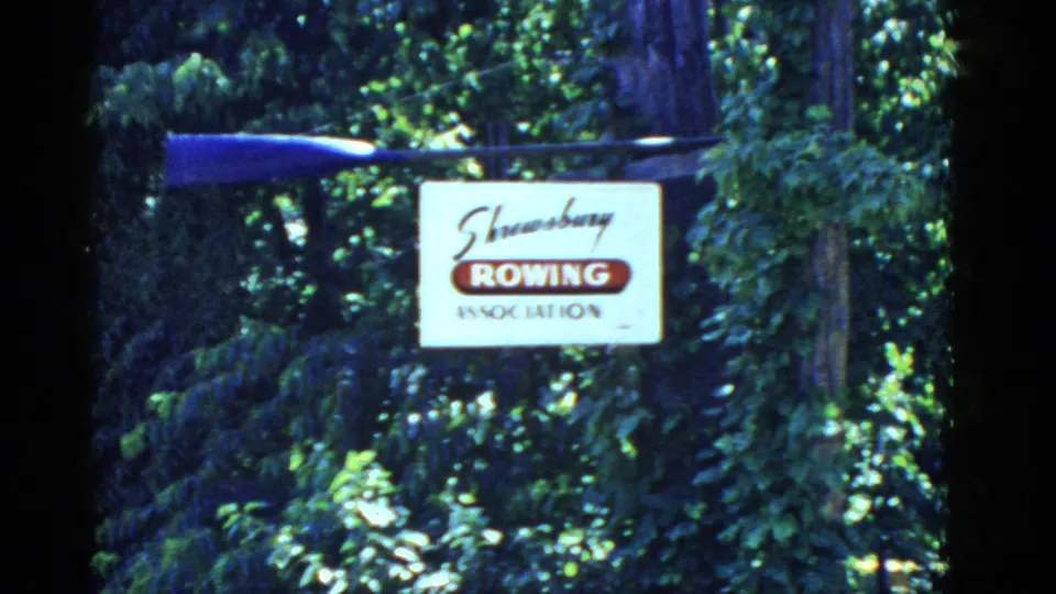 Second view of the Shrewsbury Rowing Association sign with a blue oar above it, filmed outdoors in bright 1951 home-movie color.