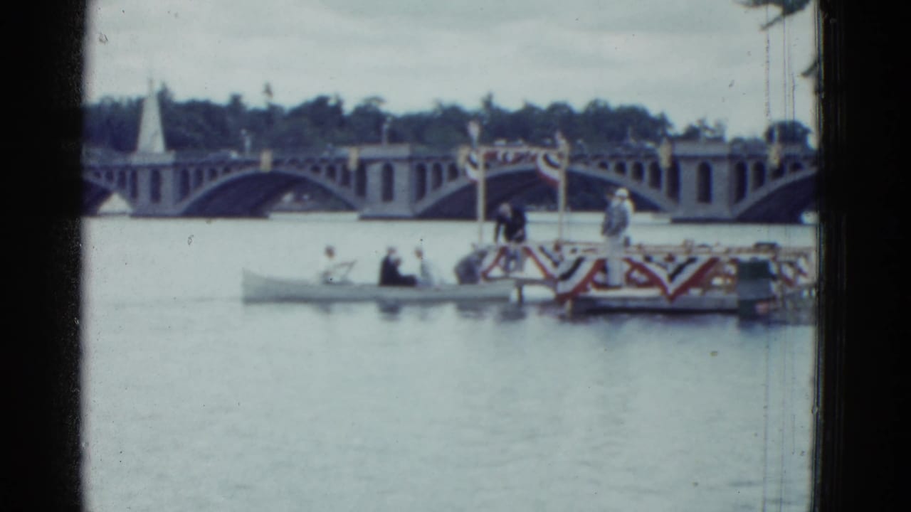 1951 Boston 8mm frame showing rowers near a decorated finish area on a river, with an arched bridge and trees in the background.