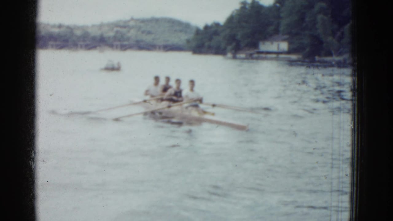 1951 Boston-area home-movie frame of a four-man crew rowing in unison on a tree-lined river.