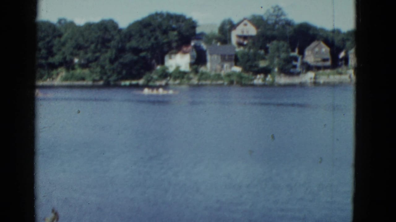 Wide lake view with distant shoreline houses and a small boat on the water.