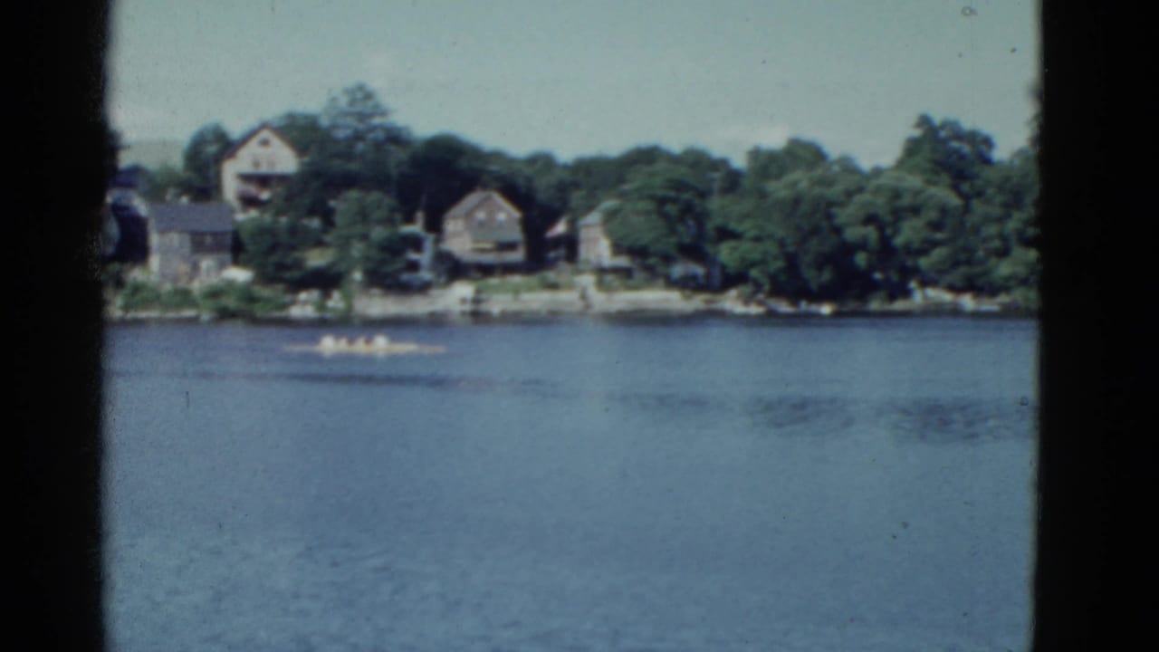 River view with distant houses, trees, and a small boat near the far shoreline.