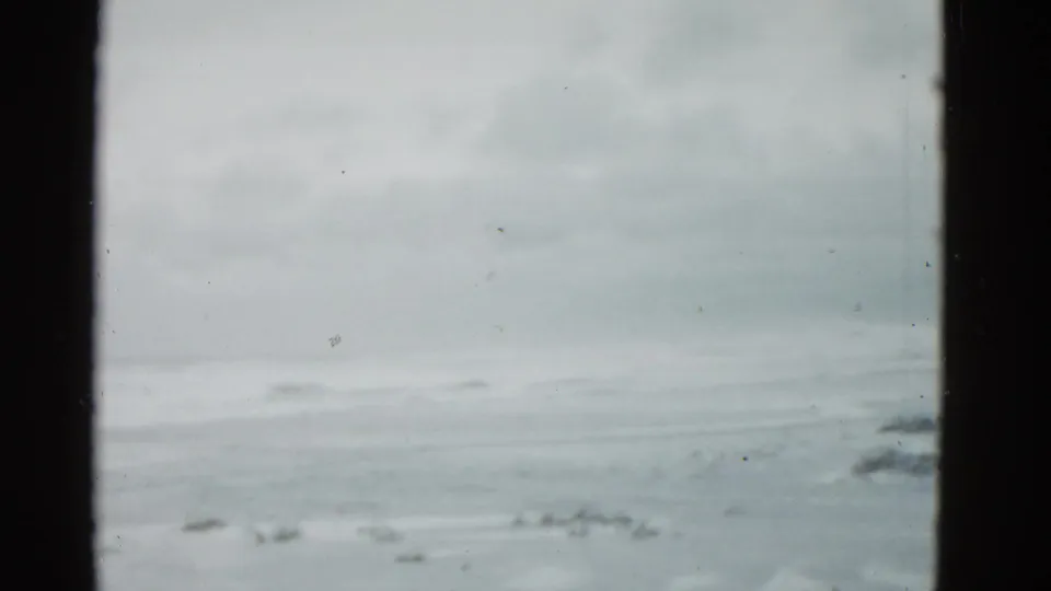 Soft 8mm frame showing a pale horizon or shoreline-like view before the street activity begins.