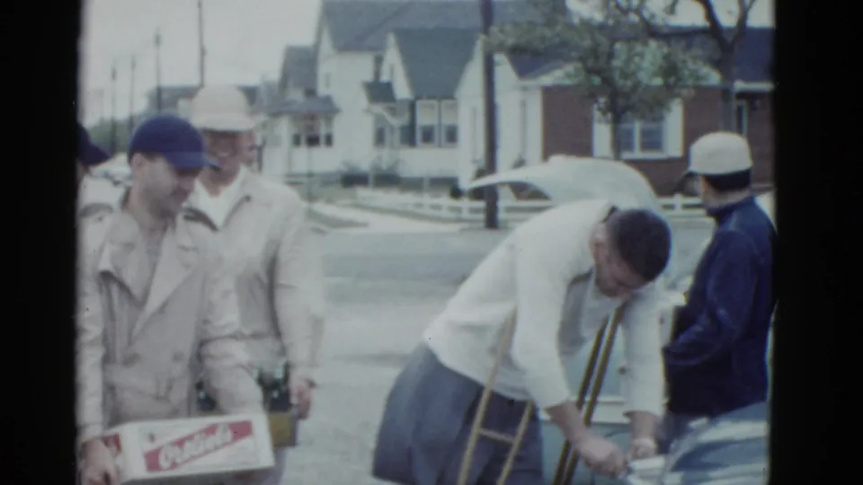 Young men in mid-century clothing handle a branded soda carton and bottle crates near a parked car in the Boston 1951 clip context.