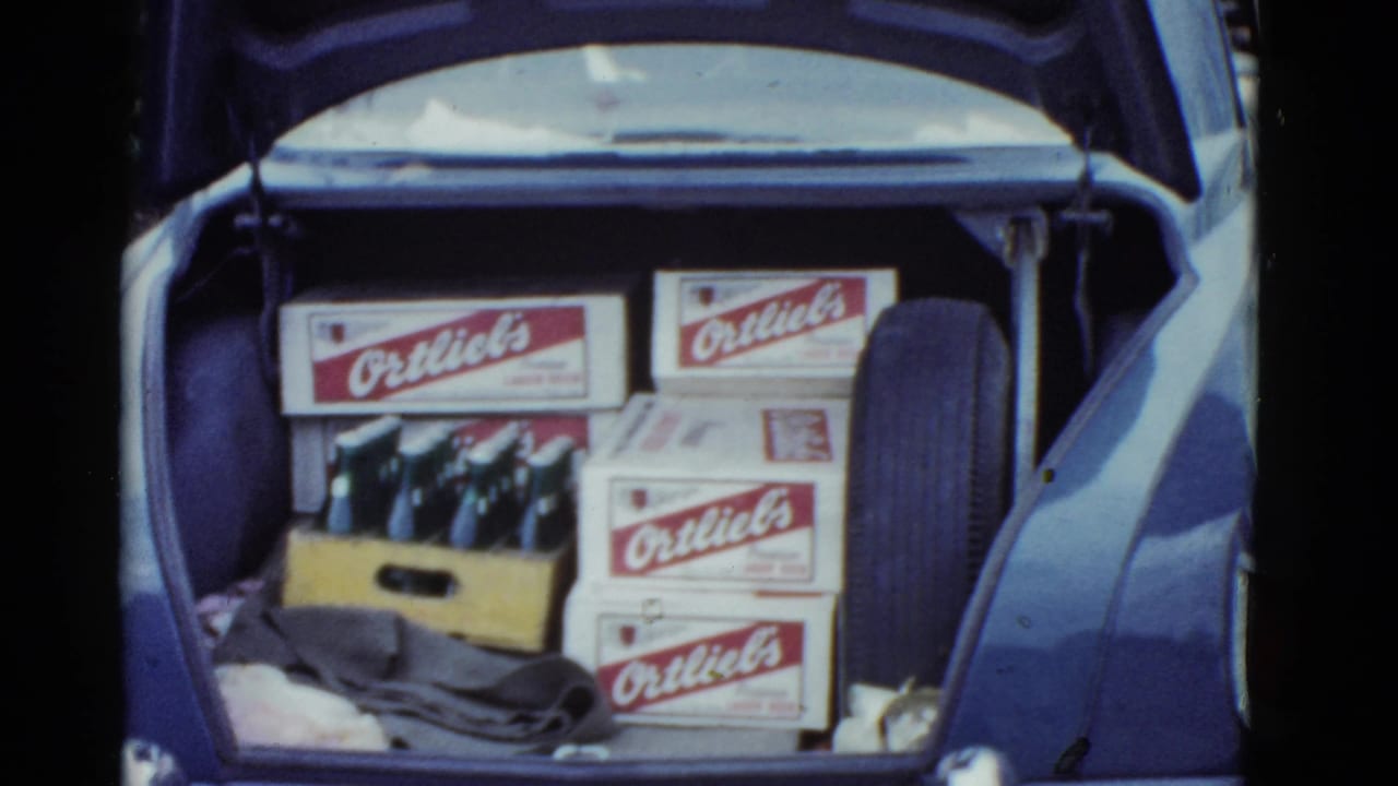 Open trunk with several Ortlieb's boxes, glass bottles in a crate, cloth, and a spare tire.