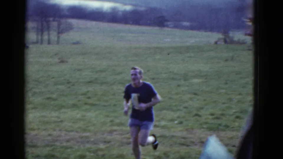 Near the end of the 1951 Boston clip, the dark-shirted runner passes close by while a foreground figure partly obscures the right edge.