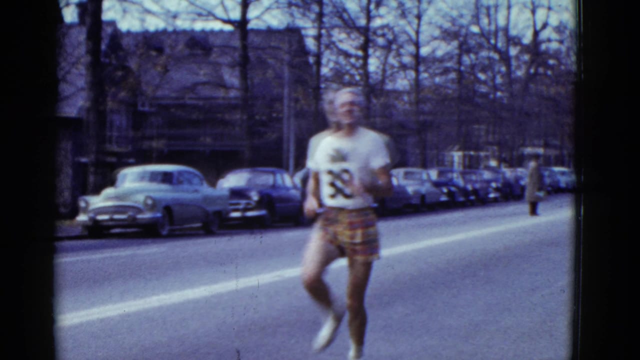 In the stated 1951 Boston footage, a runner in a white shirt and patterned shorts approaches along a road lined with parked cars.