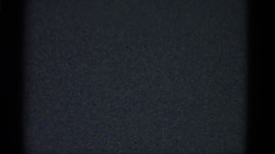 A near-black 8mm frame closes the Boston family reunion clip, showing only film grain and faint exposure variation.