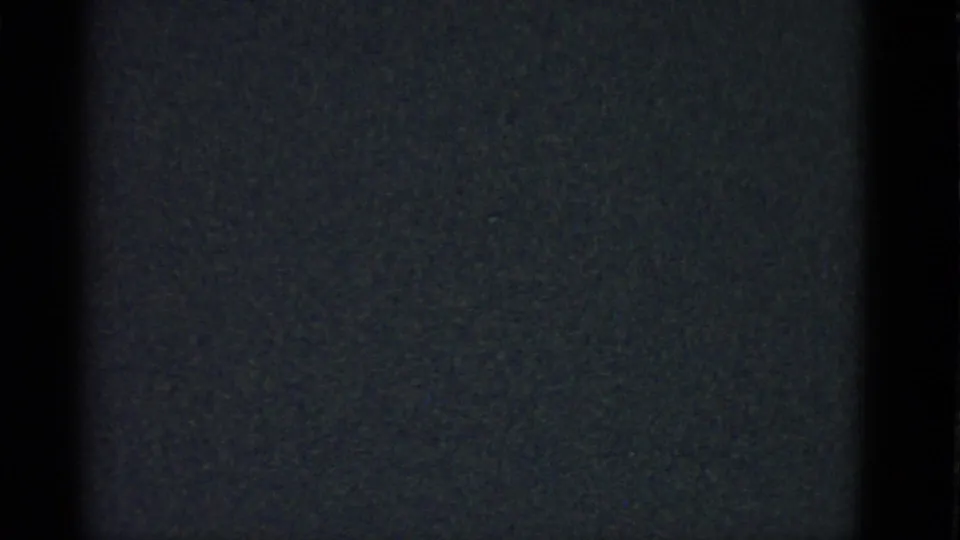 Dark, grainy 8mm frame from the Boston 1951 clip with only vertical interior shadows faintly visible.
