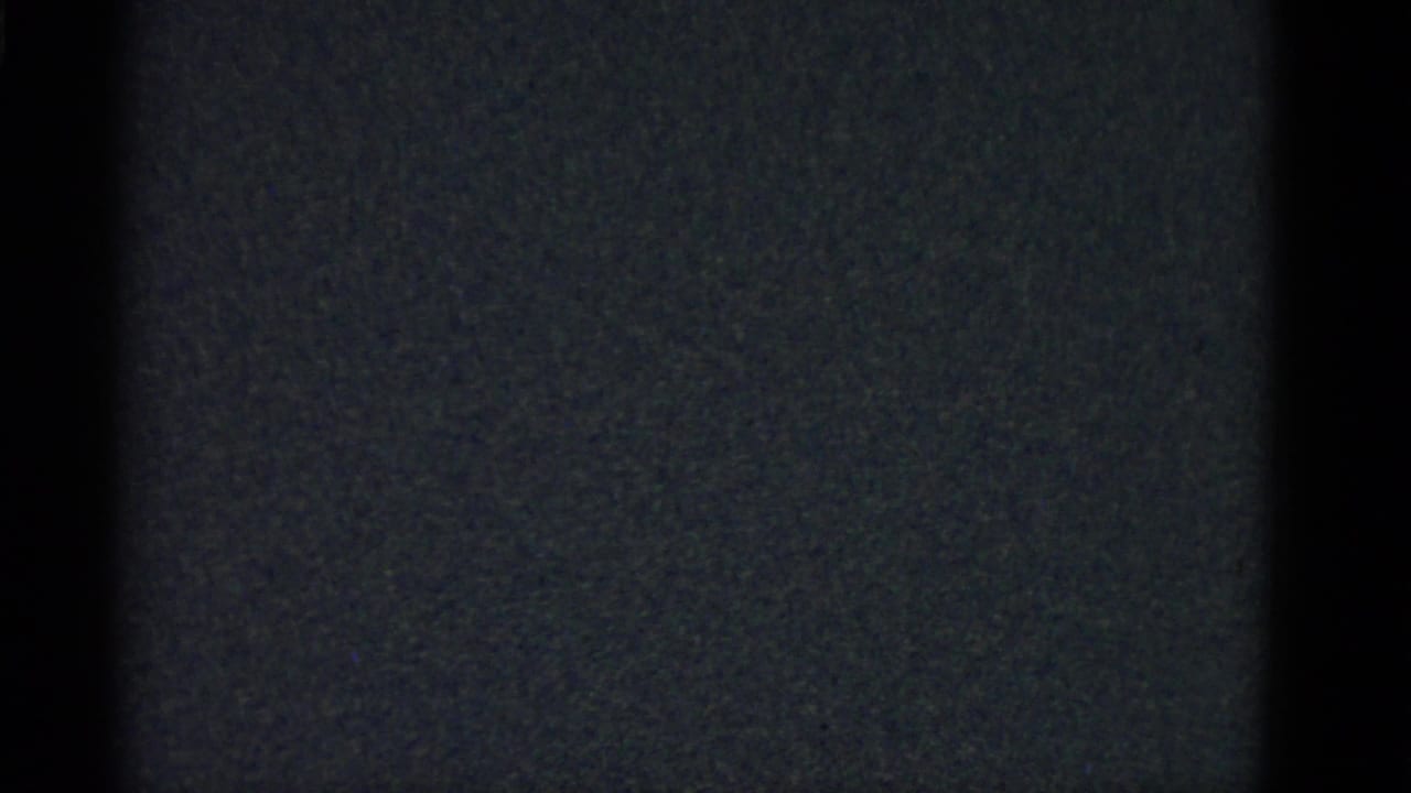 Low-light 8mm frame from the Boston 1951 footage showing dark vertical forms with no clear subject detail.