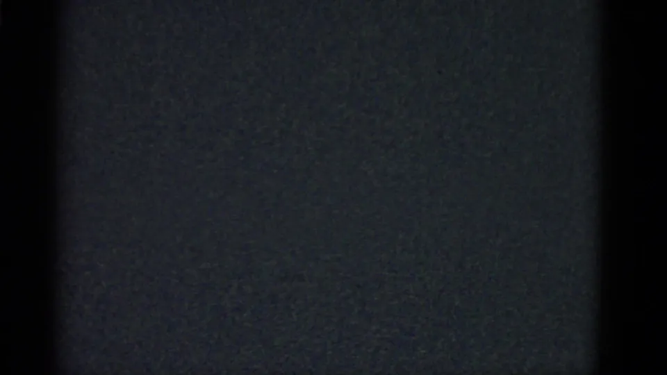 Boston 1951 home-movie frame showing a man in a light shirt from behind inside a very dark interior.