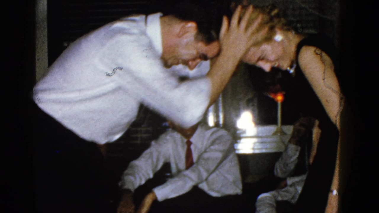 A man touches a woman's head as they lean over an indoor game setup.