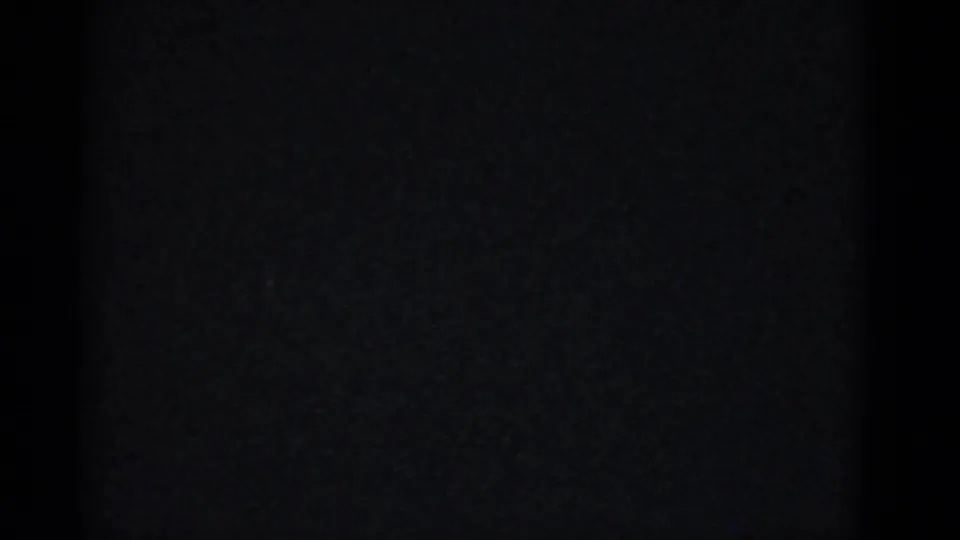 Mostly dark 8mm frame from the reunion clip, with minimal discernible detail and only faint film texture visible.