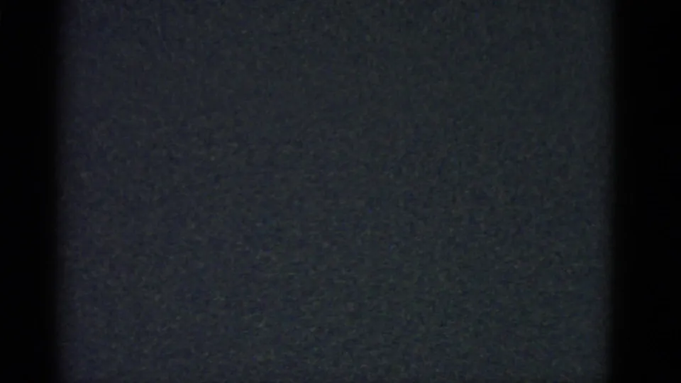 Dark 1951 Boston-labeled 8mm home-movie frame with muted grain, black side shading, and scattered tiny particles.