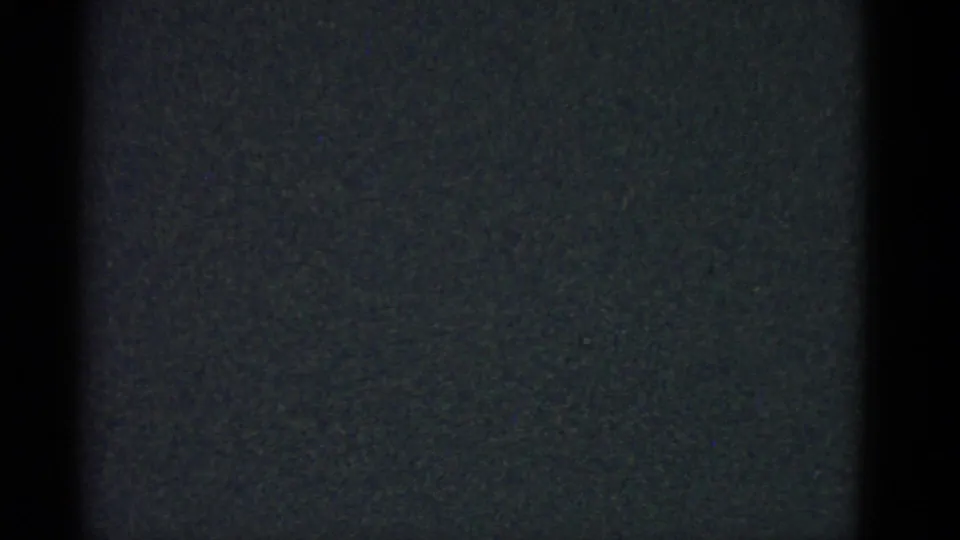 Dark, underexposed 8mm frame from the 1951 Boston home movie, with film gate edges and no clear human subject visible.