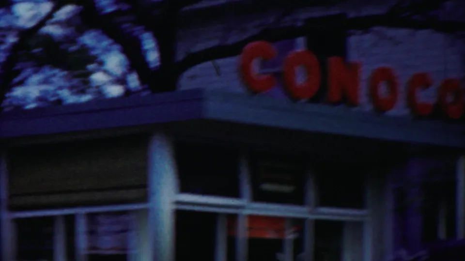 Roadside frame in Cheyenne County, Kansas showing part of a Conoco station sign, roofline, windows, and trees above.