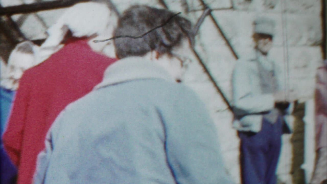Brief, blurry home-movie view of people walking outdoors in Cheyenne County, Kansas, including a person in a light blue coat and others in winter clothing.