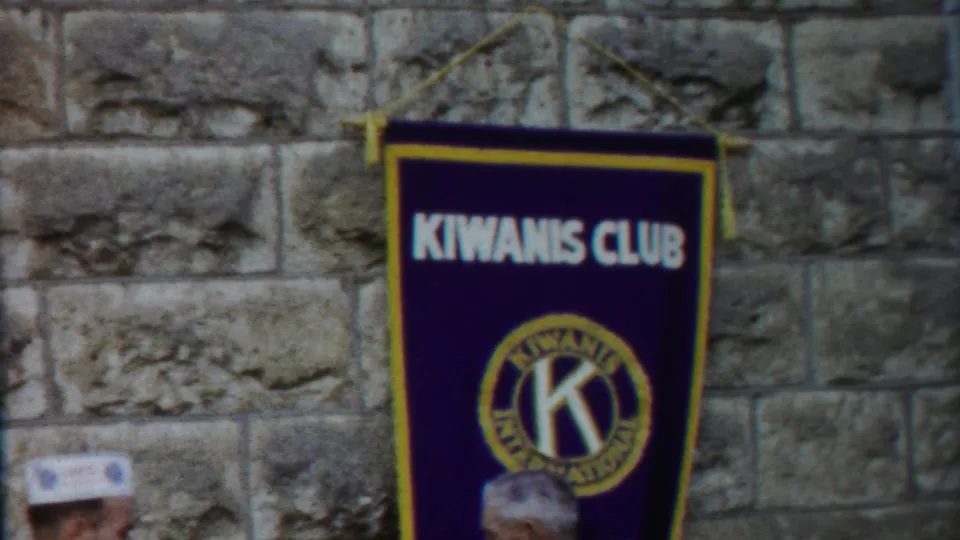 A 1958 Kansas 8mm frame shows the Kiwanis Club banner against stonework, with only a partial attendee visible at the bottom.