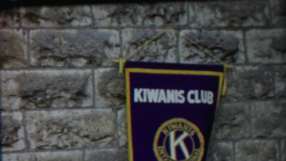 Final 1958 Kansas frame with the Kiwanis Club banner shifted to the right against a rough stone wall.