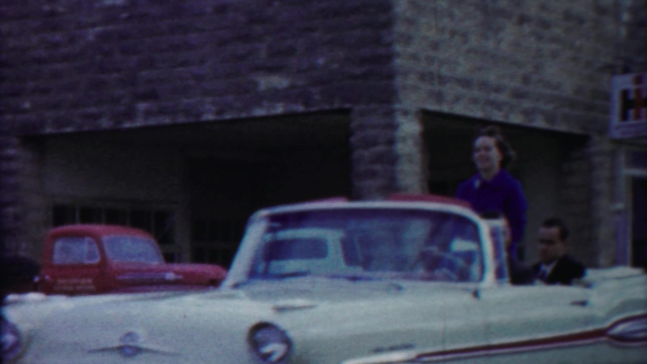 The convertible is seen from the front with a woman standing behind it and a suited man near the passenger side in Cheyenne County, Kansas.