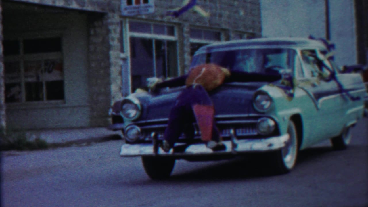 Closer 1958 Cheyenne County frame with the boy across the hood of a two-tone car, chrome bumper visible in front.