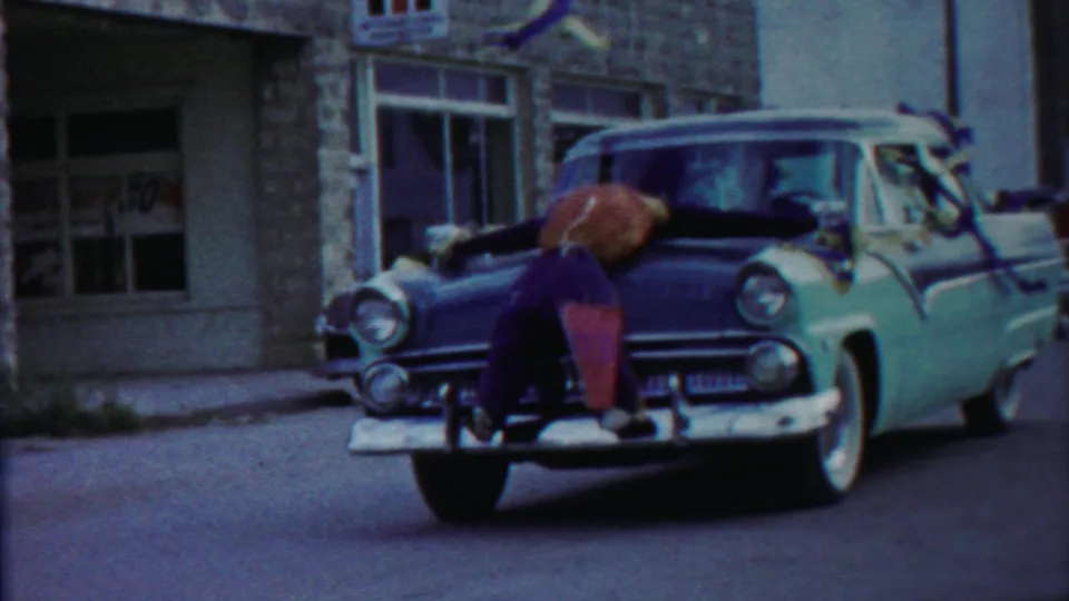 Closer 1958 Cheyenne County frame with the boy across the hood of a two-tone car, chrome bumper visible in front.