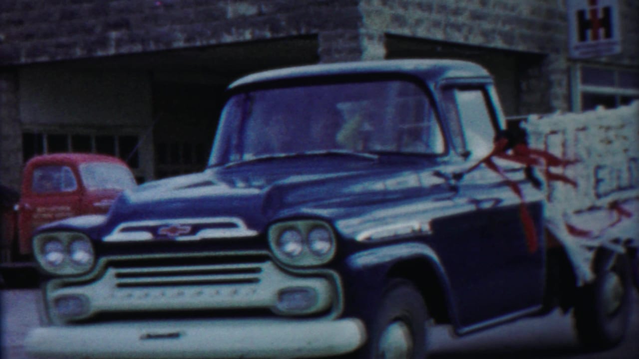 Blue Chevrolet pickup fills the frame in a 1958 Cheyenne County, Kansas street scene, with strapped white cargo behind the cab.