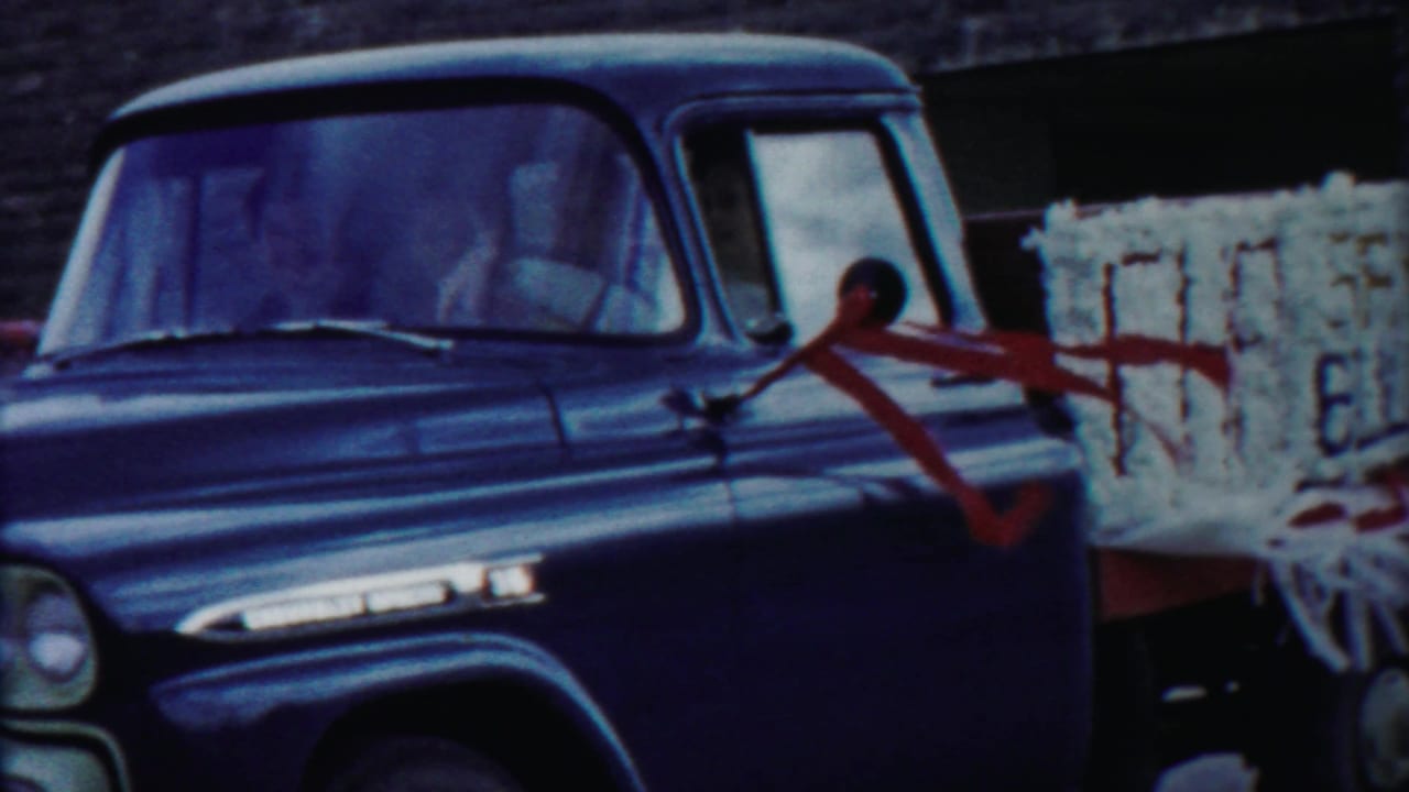 The blue pickup passes close to the camera in Cheyenne County, Kansas, with red straps crossing pale cargo behind the cab.