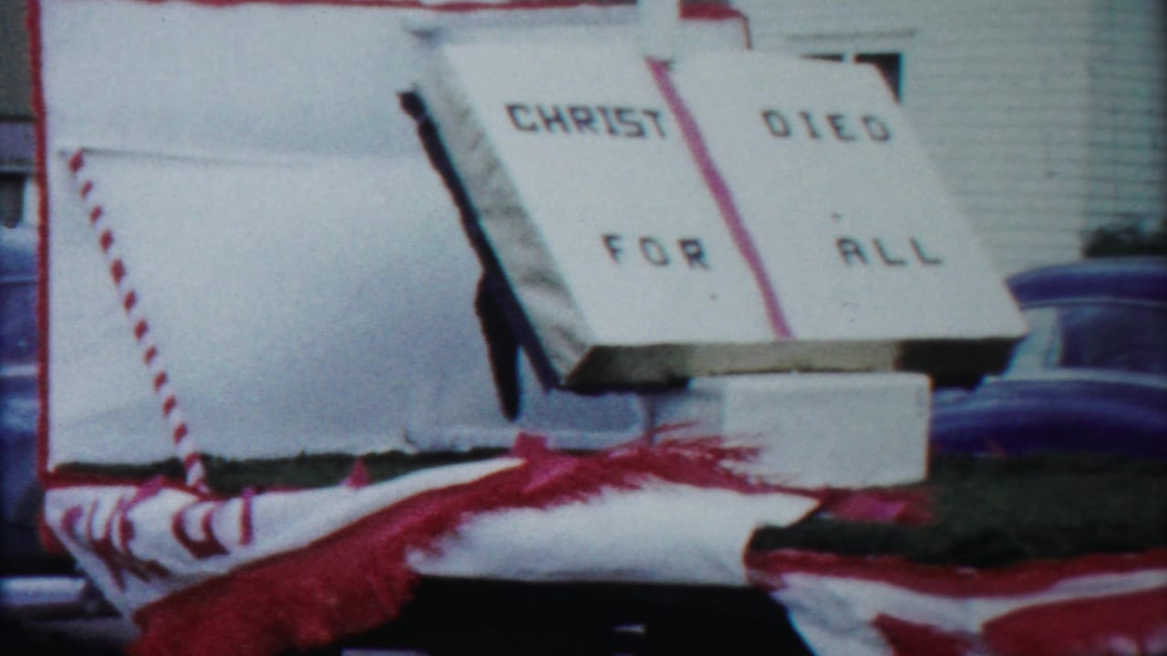 The final frame shows the church parade float's CHRIST DIED FOR ALL sign with red fringe and a blue sedan in the background.