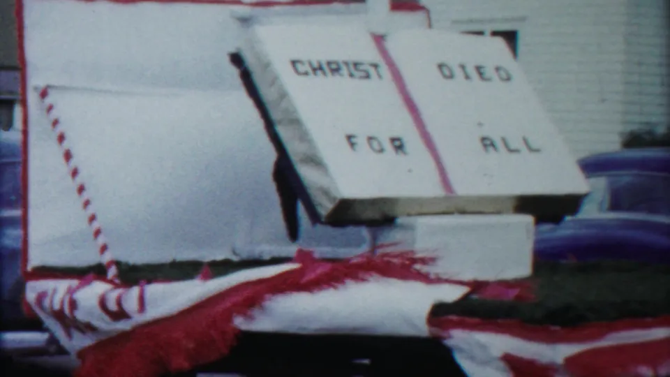 The final frame shows the church parade float's CHRIST DIED FOR ALL sign with red fringe and a blue sedan in the background.