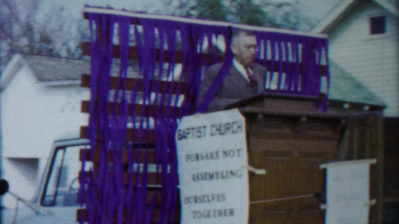 The final frame shows a man speaking from a pulpit on a decorated Baptist Church float in the 1958 Kansas footage.