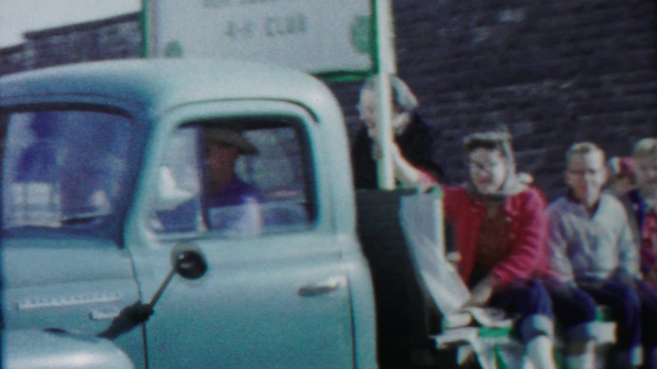 Pale blue pickup in the Cheyenne County 1958 parade with adults riding in back and a partially visible 4-H Club sign above.