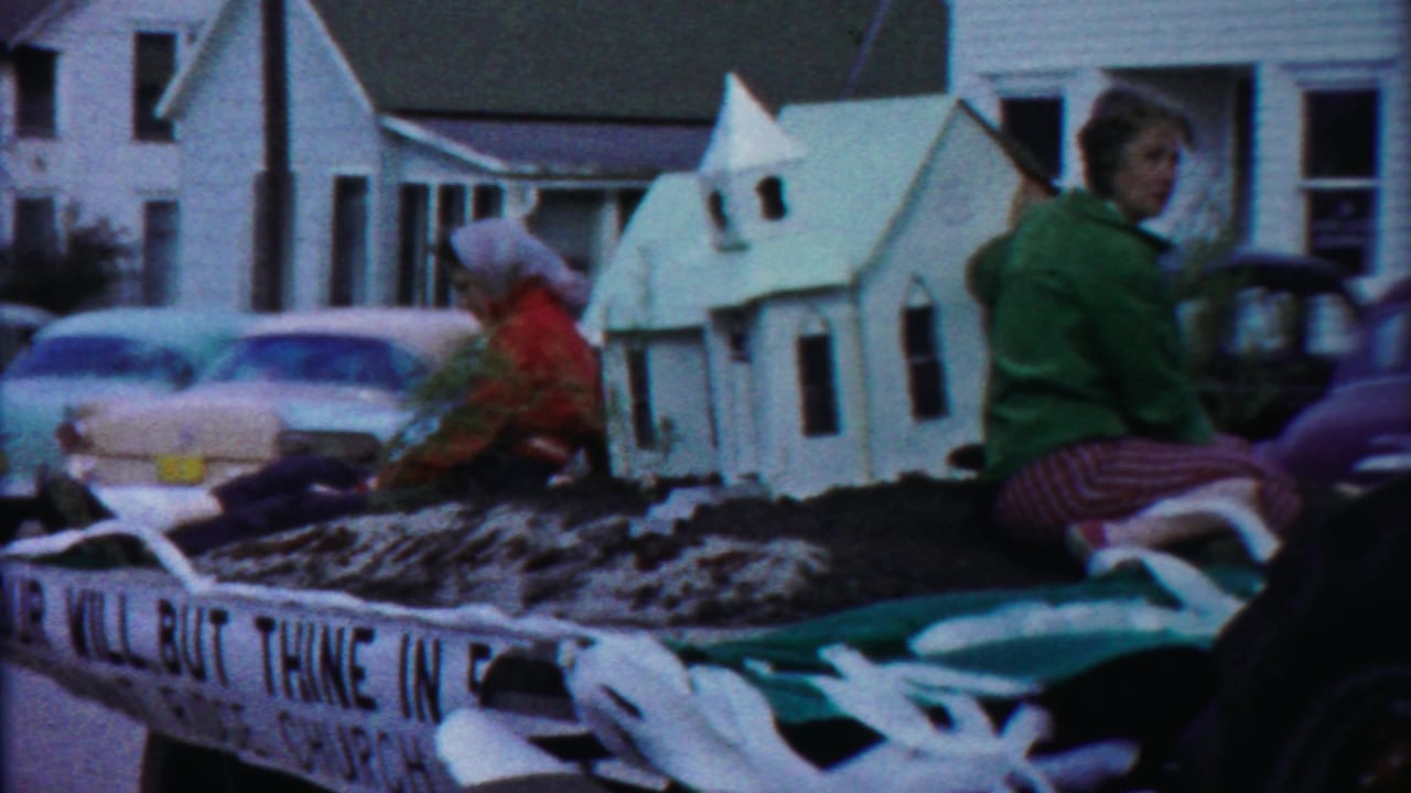 1958 Cheyenne County parade float with miniature white church displays, two seated women, classic cars, and partial banner text.