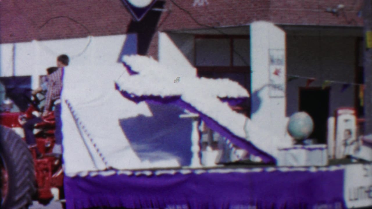 1958 Cheyenne County, Kansas parade frame with a red tractor pulling a white and purple St. Paul's Lutheran Church float along a commercial street.