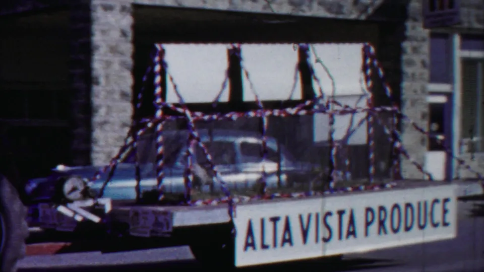 1958 Cheyenne County, Kansas parade float with caged pigs, patriotic streamers, and Alta Vista Produce signage on a town street.