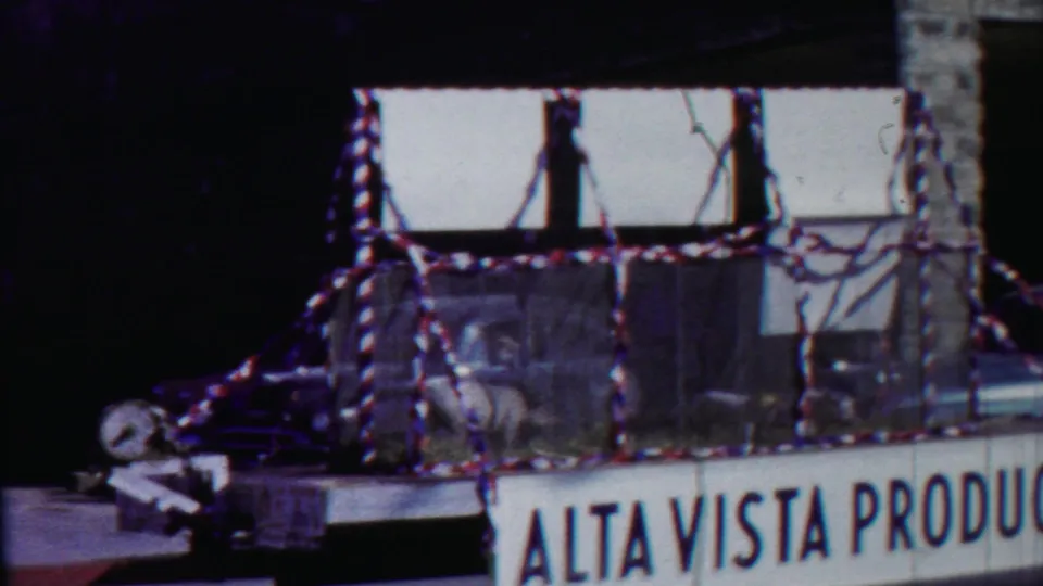 Side view of the decorated pig float in 1958 Cheyenne County, Kansas, with partial Alta Vista Produce lettering and street buildings behind it.