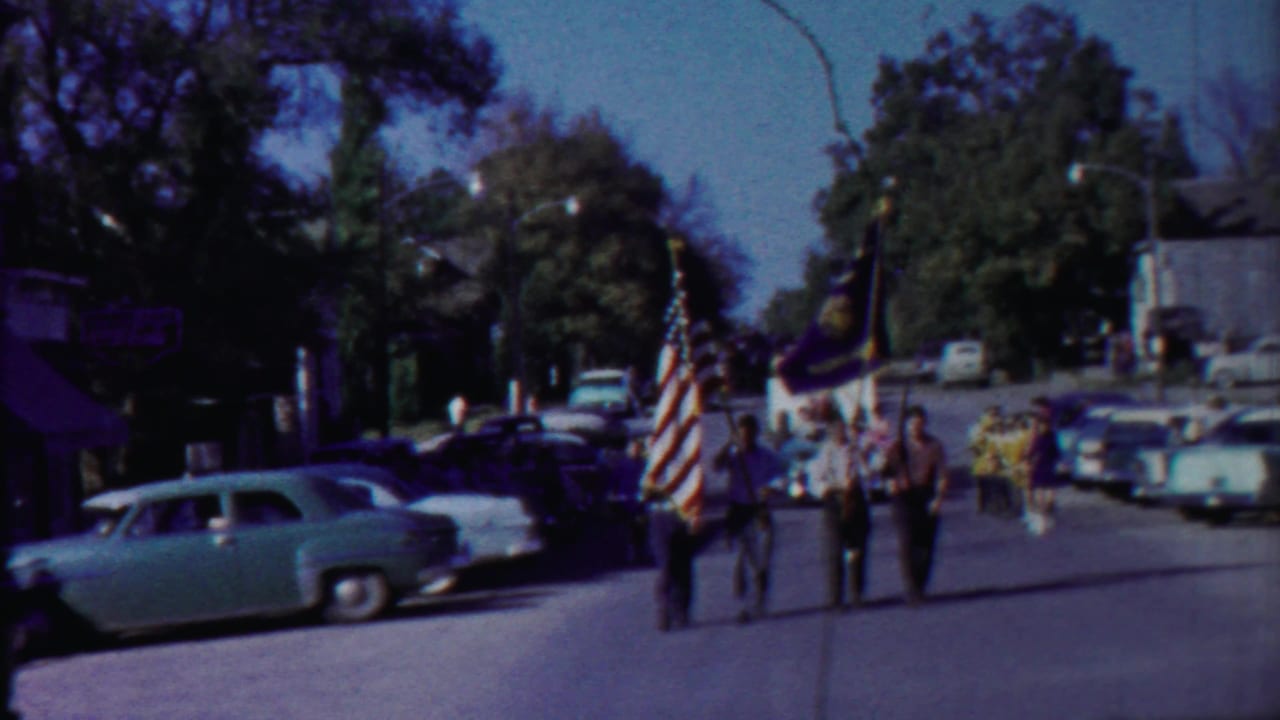 Men march down a street carrying the American flag and other banners.