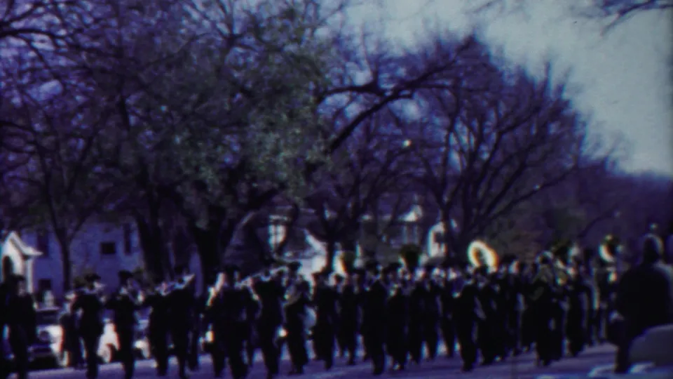 Cheyenne County parade footage shows the band crossing the frame under winter-bare trees and soft 8mm color.