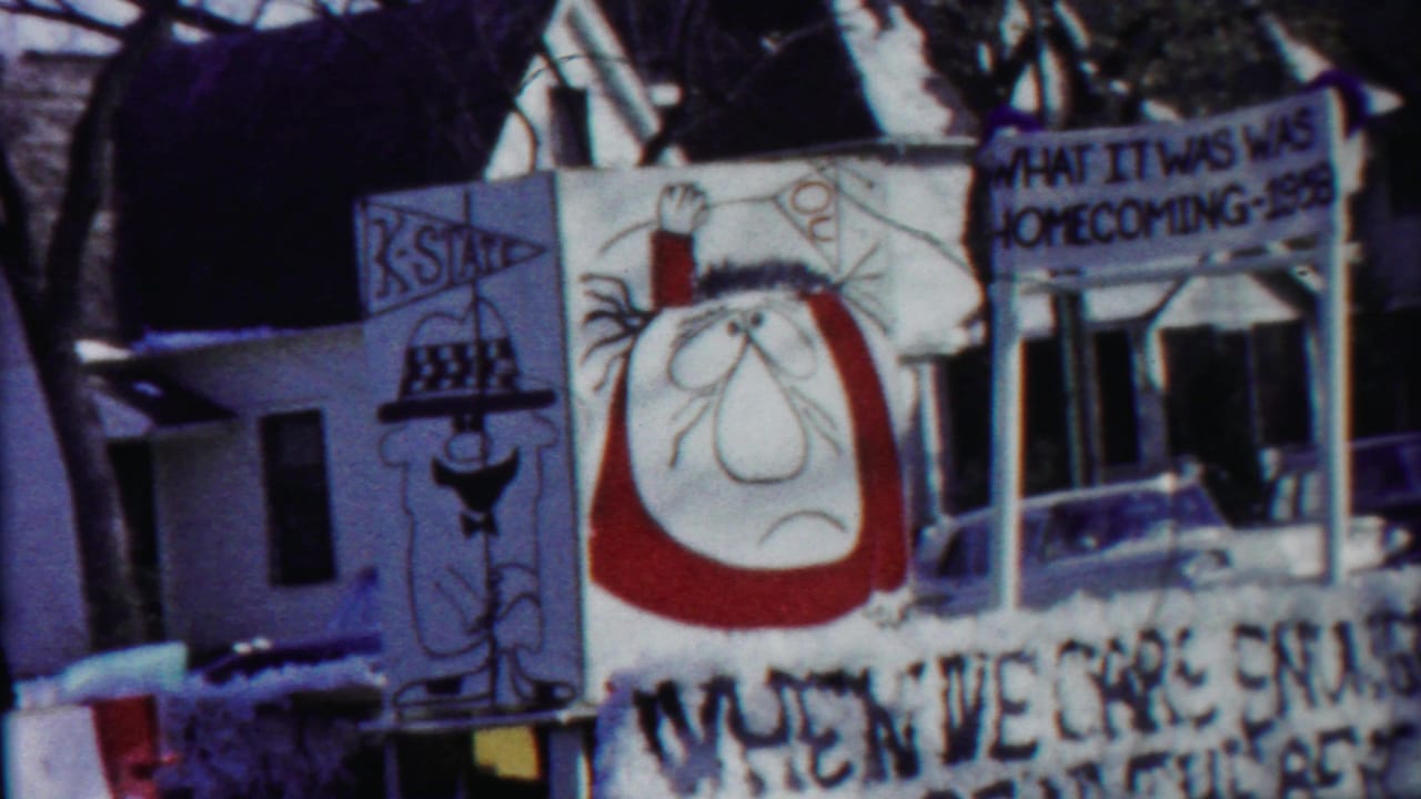Close 8mm view of the Kansas homecoming parade float, showing hand-drawn character art and partially readable painted signage.
