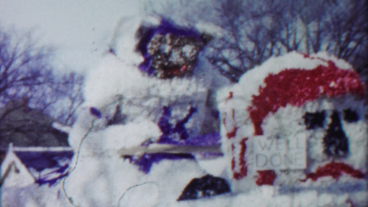 1958 Kansas parade float detail with a large white figure and a red-trimmed floral structure bearing the words WELL DONE.