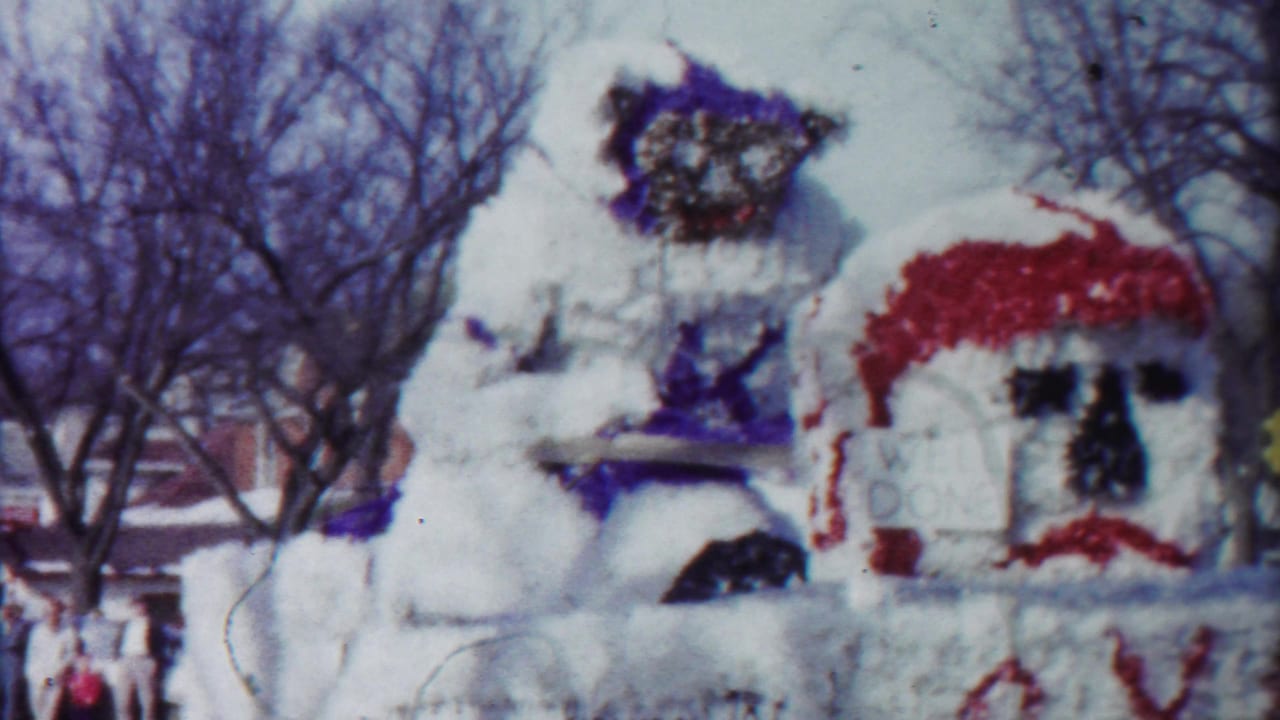 1958 Cheyenne County, Kansas home-movie frame of a decorated parade float with a large white figure and WELL DONE sign structure.