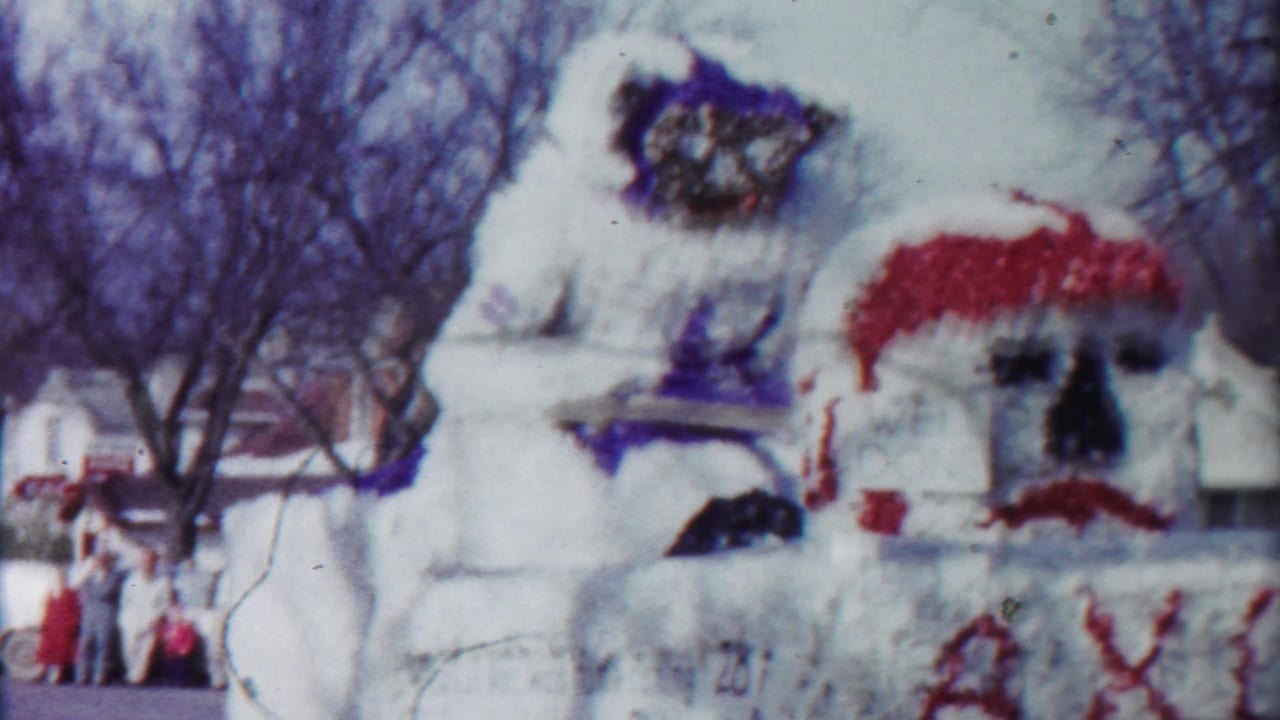 1958 Cheyenne County, Kansas parade float with white decorations, red accents, and a large painted figure passing a wintery residential street.