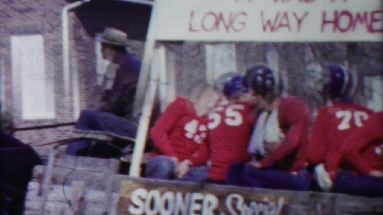 Football players in red jerseys sit in a horse-drawn carriage during a parade.
