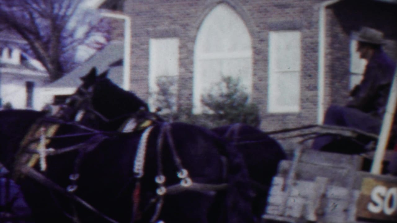 Horse team pulling the football players' carriage past a brick building in the 1958 Cheyenne County, Kansas parade footage.