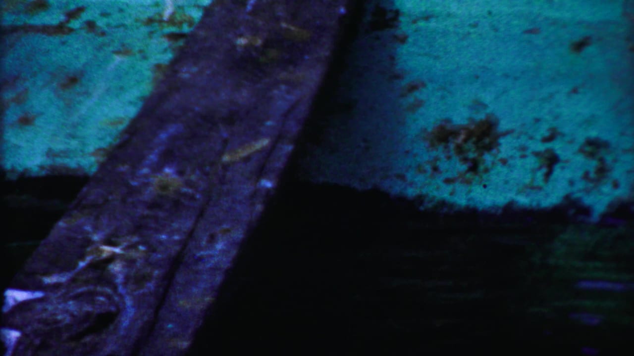 Close dark view of weathered boards or stone with blue-green color shift.