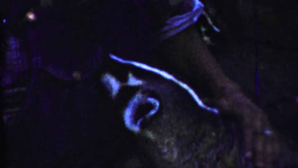 Low-light 8mm close view inside the enclosure, with a bear-like animal partly visible and a pale curved highlight on its head or body.