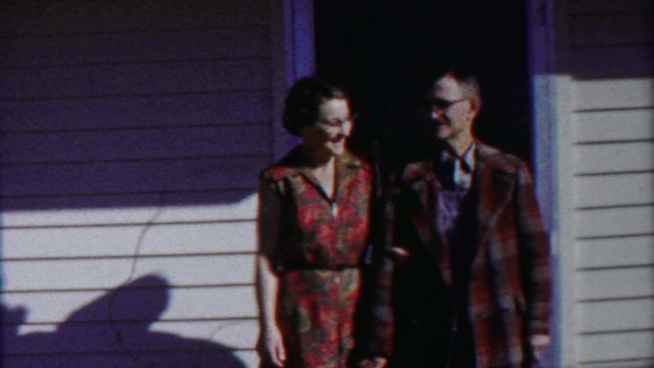 In 1958 Cheyenne County, Kansas footage, an adult couple stands at a white-sided house doorway in bright sun.